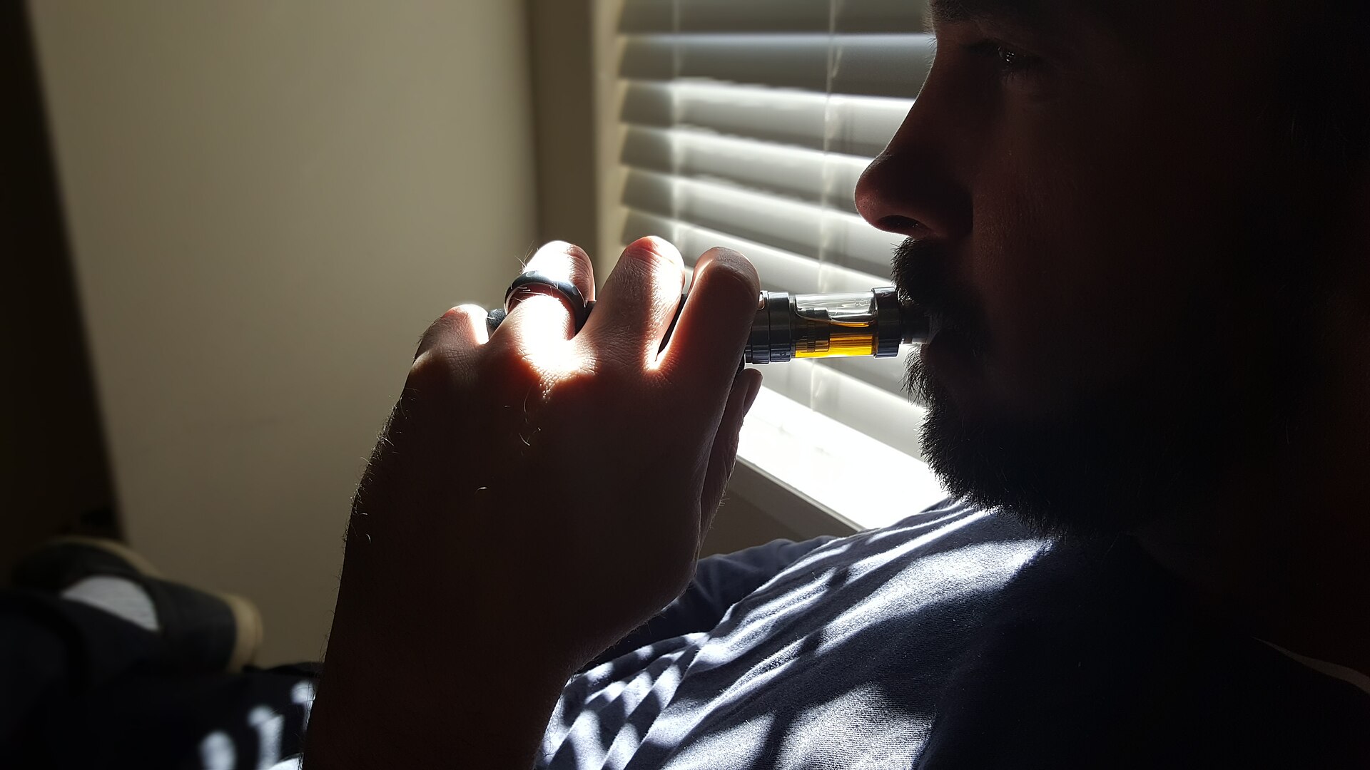An adult using a vapor device indoors